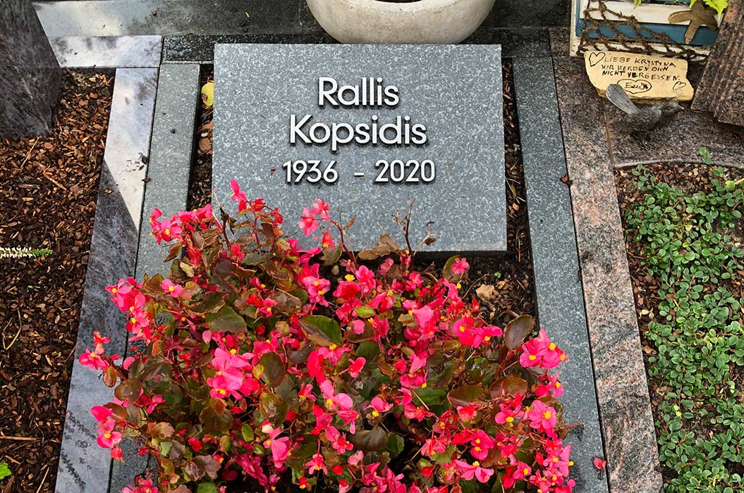 Grabstein von Rallis Kopsidis, dunkelgrau mit Blumen und Inschrift, Jahrzahlen 1936–2020.