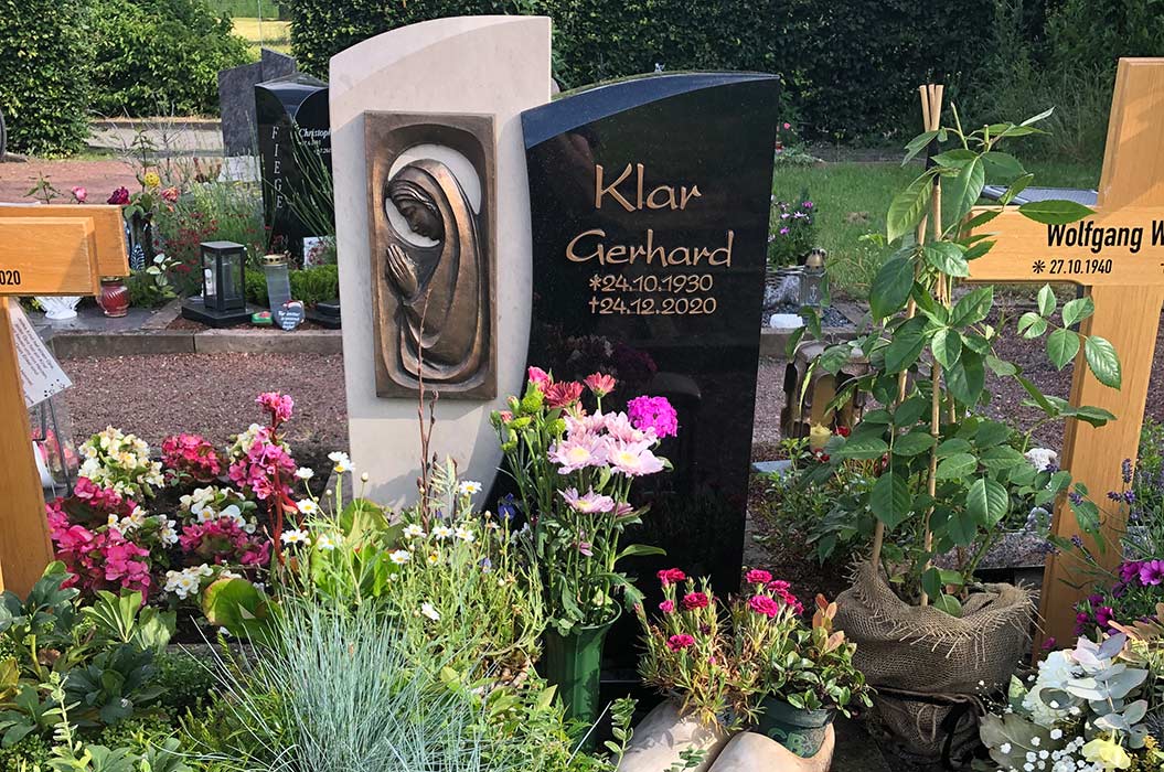 Ein Grabstein mit Blumen, einer Skulptur und der Inschrift "Klar Gerhard".