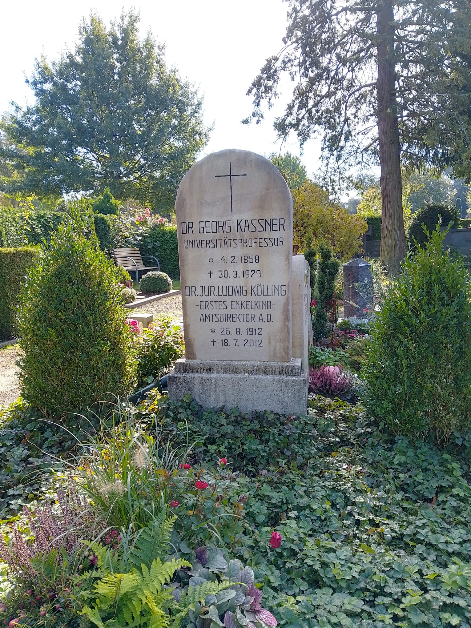 Grabstein mit Inschrift für Dr Georg Kassner und Dr Jurtjohw Köhling auf grünem Friedhof